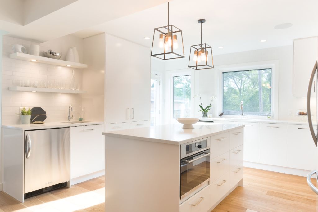 Custom white kitchen with open shelving, integrated bar area, and a spacious island