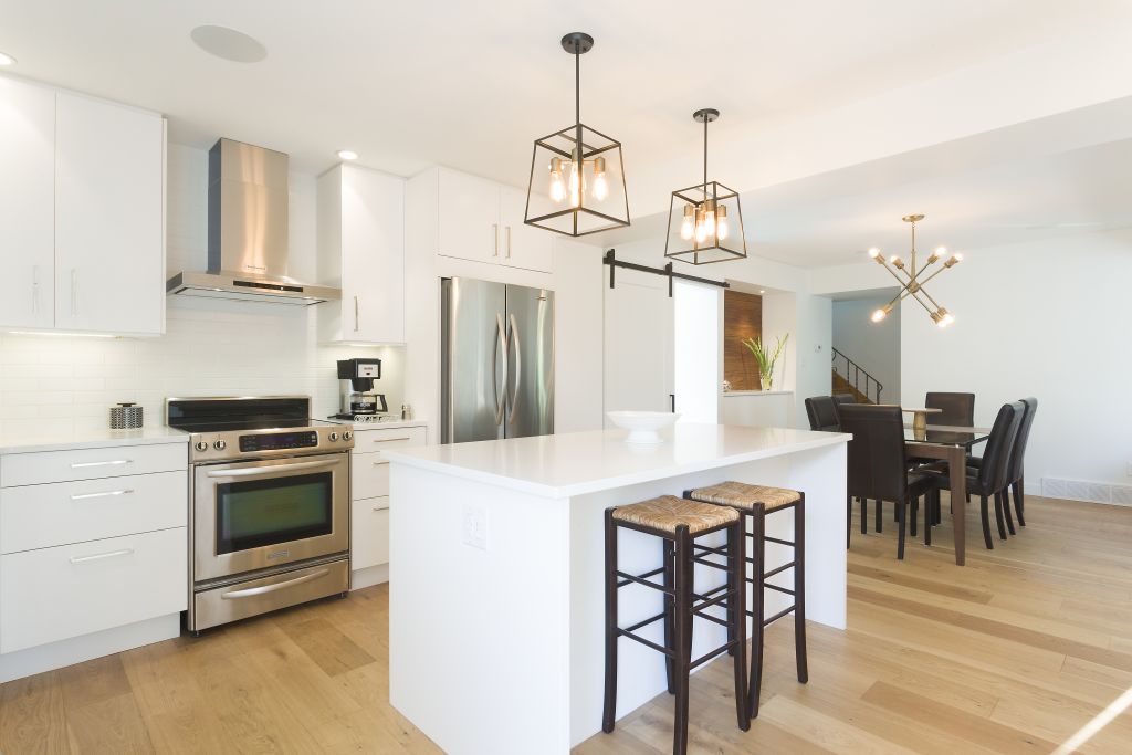 Custom white kitchen with stainless appliances and a spacious island overlooking the dining area