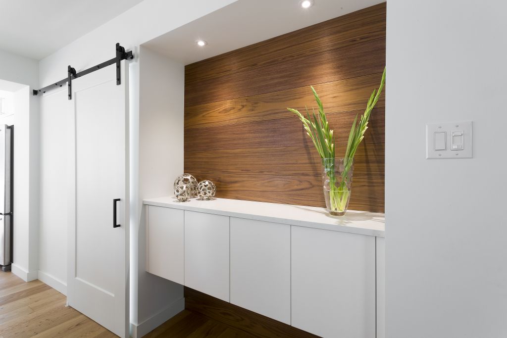 Bright hallway with wood feature wall, barn sliding door, and sleek floating storage.