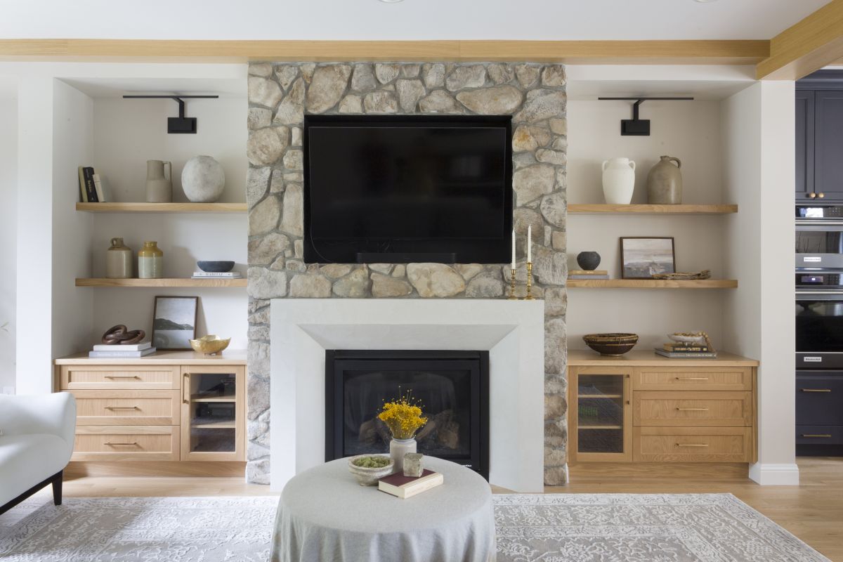 Custom stone fireplace with built-in shelving, oak cabinetry, and modern styling in a new construction home