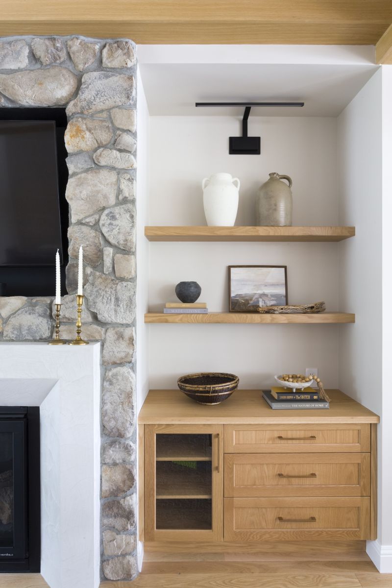 Living room detail of wood cabinetry and shelving integrated with a rustic stone fireplace surround
