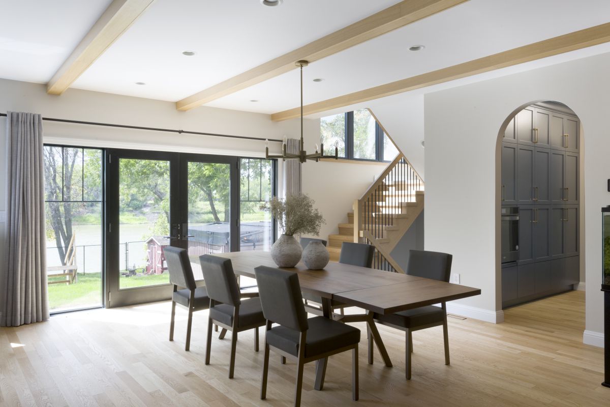 Custom dining room with modern wood beams, large black-framed patio doors, and built-in cabinetry with arched detailing