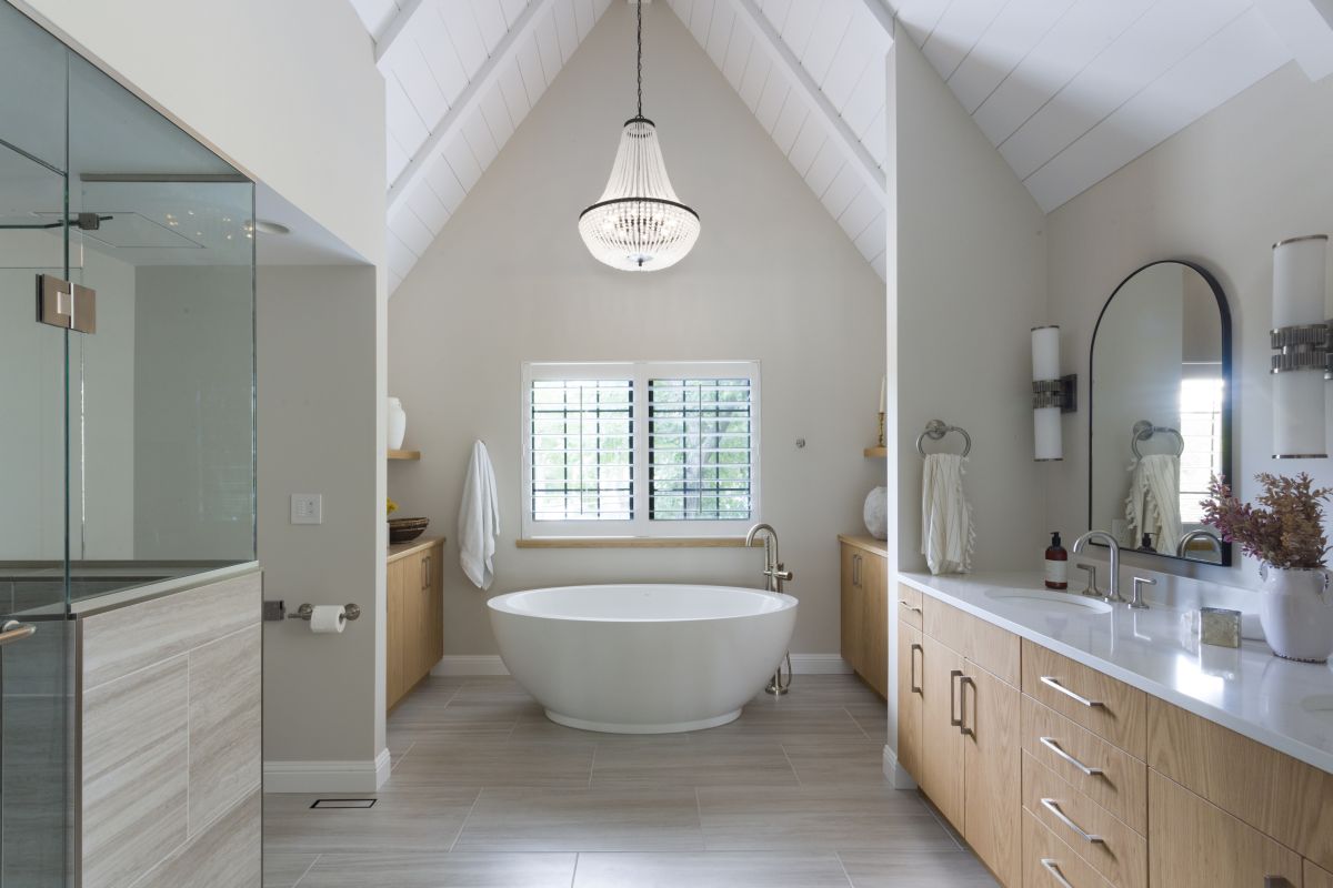 Modern bathroom with vaulted ceiling, freestanding soaking tub, glass shower, and wood double vanity