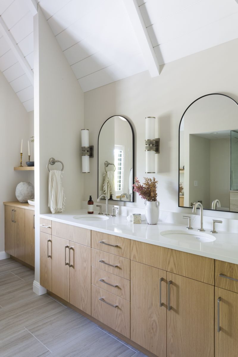 Contemporary bathroom vanity featuring dual sinks, natural wood cabinetry, and modern wall sconces.