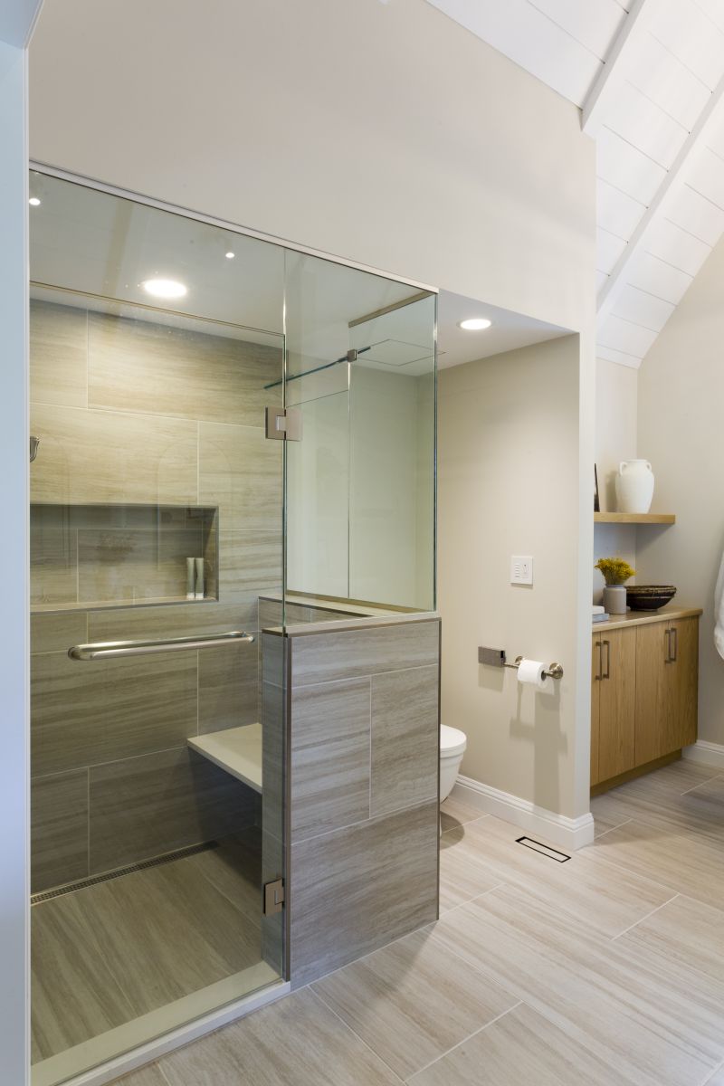 Luxury bathroom featuring glass shower with bench seating and custom millwork cabinetry