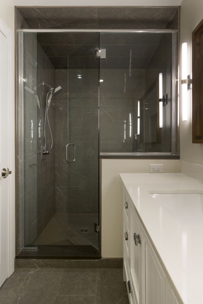 Sleek walk-in shower with frameless glass door and floor-to-ceiling gray tile