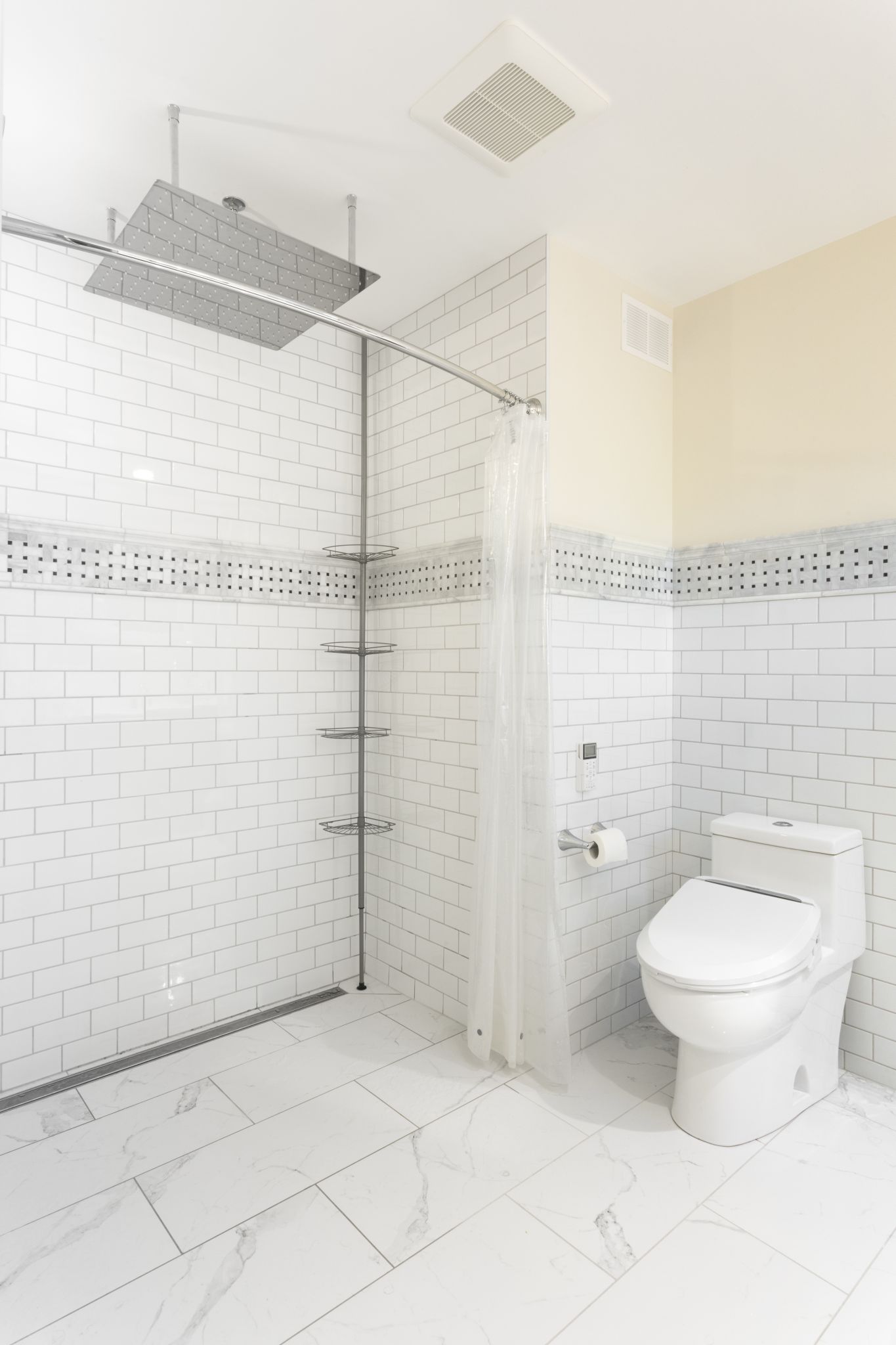 Modern bathroom with large rainfall showerhead, subway tile walls, marble look floor tiles.