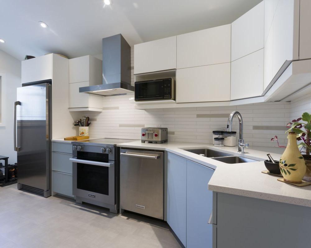 Custom renovation with light blue cabinets, white tiled backsplash and silver accessories